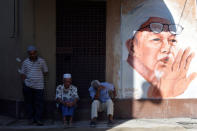 People sit next to a mural of the late former Party Islam Se-Malaysia (PAS) president, Tuan Guru Nik Abdul Nik Mat at Medan Ilmu in Kota Bharu, Kelantan, Malaysia April 13, 2018. Picture taken April 13, 2018. REUTERS/Stringer