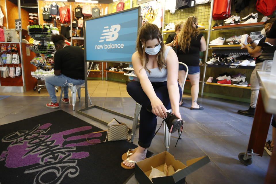 Allie Arredonodo, wears a face mask as she tries on shoes at Journey's shoe store in the Yuba Sutter Mall in Yuba City, Calif., Wednesday, May 6, 2020. Several dozen shoppers streamed into the first California mall to reopen Wednesday, despite Gov. Gavin Newsom's orders restraining businesses because of the coronavirus pandemic. (AP Photo/Rich Pedroncelli)