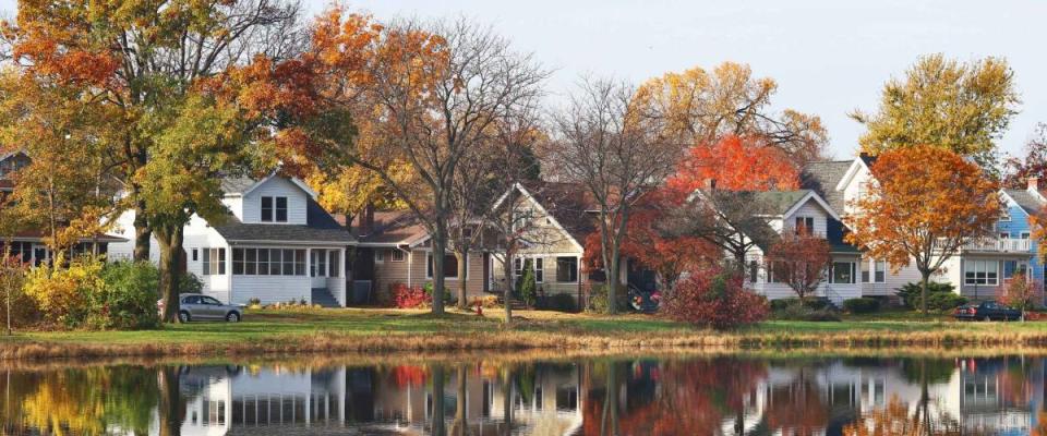 Fall cityscape with private houses neighborhood along a pond. Colorful trees and houses reflected in a water. Midwest USA, Wisconsin. Classic american middle class homes background.