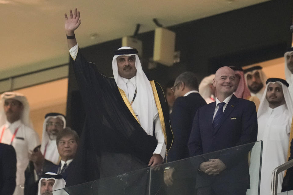 Sheikh Tamim bin Hamad Al Thani waves next to FIFA President Gianni Infantino prior to the opening World Cup opening match between Qatar and Ecuador at the Al Bayt Stadium in Al Khor , Qatar, Sunday, Nov. 20, 2022. (AP Photo/Manu Fernandez)