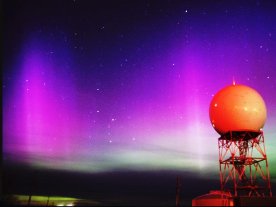 A picture from Riverton's national weather service in Wyoming shows purple and green northern lights shining behind a spherical structure in the foreground.