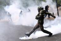 Police kicks a tear gas canister during a protest against the increase in subway ticket prices in Santiago