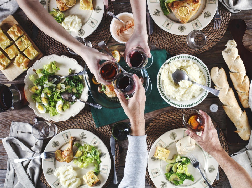 People clinking glasses over dinner.