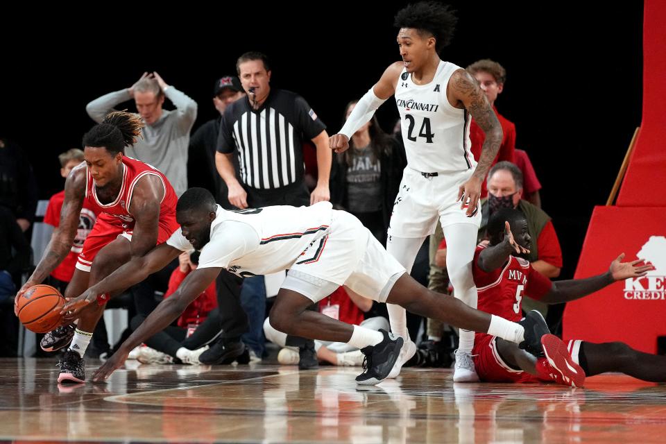 Miami (Oh) Redhawks forward Dalonte Brown (13) and Cincinnati Bearcats forward Abdul Ado (00) compete for a loose ball in the second half of an NCAA men's college basketball game, Wednesday, Dec. 1, 2021, at Millett Hall in Oxford, Ohio. The Cincinnati Bearcats won, 59-58.