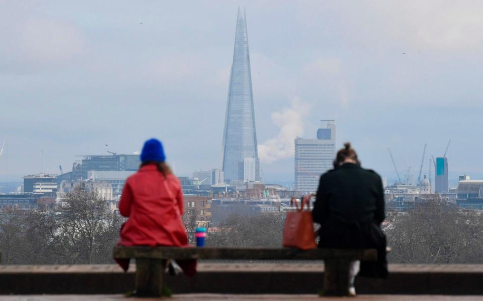 People sit at a social distance from one another on a bench on the top of Primrose Hill in London - JUSTIN TALLIS/AFP