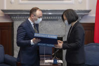 In this photo released by the Taiwan Presidential Office, Taiwanese President Tsai Ing-wen, right, exchange gifts with Matas Maldeikis, head of the Lithuanian delegation during a meeting with lawmakers from Baltic states at the Presidential Office in Taipei, Taiwan on Monday, Nov. 29, 2021. Lawmakers from all three Baltic states met with Tsai on Monday in a sign of further cooperation between European Union nations and Taiwan. (Taiwan Presidential Office via AP)