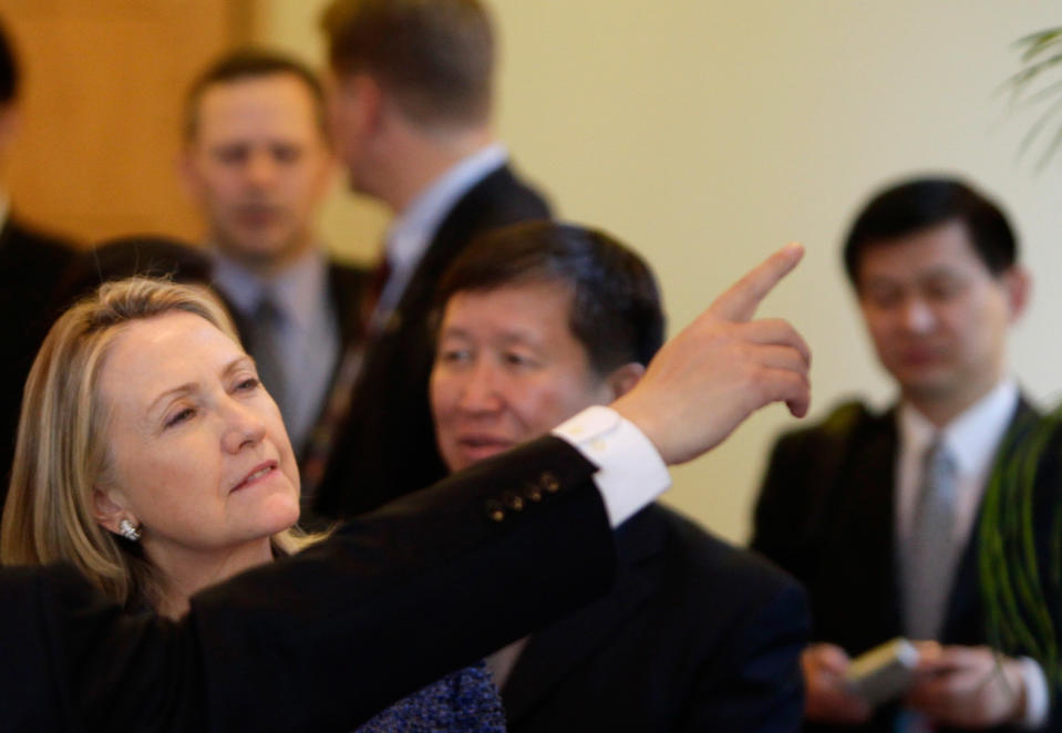 U.S. Secretary of State Hillary Clinton gestures as China's Minister of Science and Technology Wan Gang introduces a cooking stove on exhibition at Diaoyutai State Guesthouse in Beijing