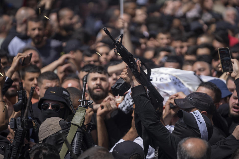 Palestinian militants from the Lions' Den armed group shoot in the air at the funeral procession of three comrades who were killed by Israeli forces earlier this year, Odai Shami, Jihad Shami and Mohammad Dabik, in the West Bank city of Nablus, Saturday, May 6, 2023. The killing of Zuhair al-Ghaleeth last month, the first slaying of a suspected Israeli intelligence collaborator in the West Bank in nearly two decades, has laid bare the weakness of the Palestinian Authority and the strains that a recent surge in violence with Israel is beginning to exert within Palestinian communities. (AP Photo/Nasser Nasser)