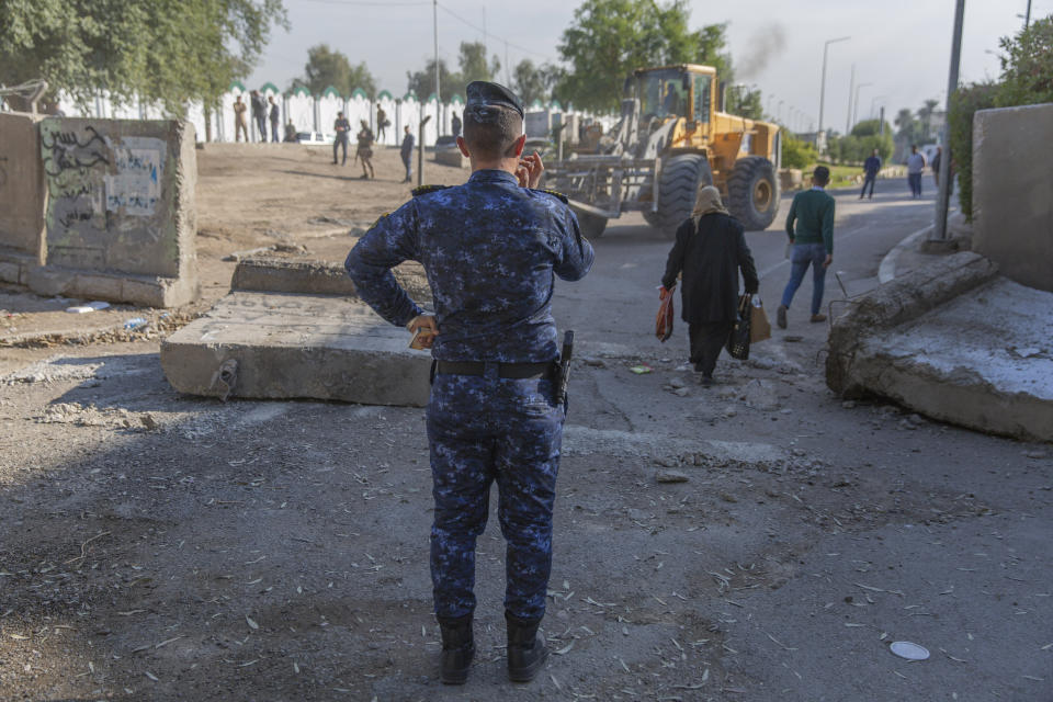 An Iraqi police officer instructs a bulldozer while Iraqi security forces remove cement blocks and opened the streets, that were closed for security concerns, around the Green Zone in Baghdad, Iraq, Thursday, Jan. 2, 2020. Iran-backed militiamen have withdrawn from the U.S. Embassy compound in Baghdad after two days of clashes with U.S. security forces. (AP Photo/Nasser Nasser)