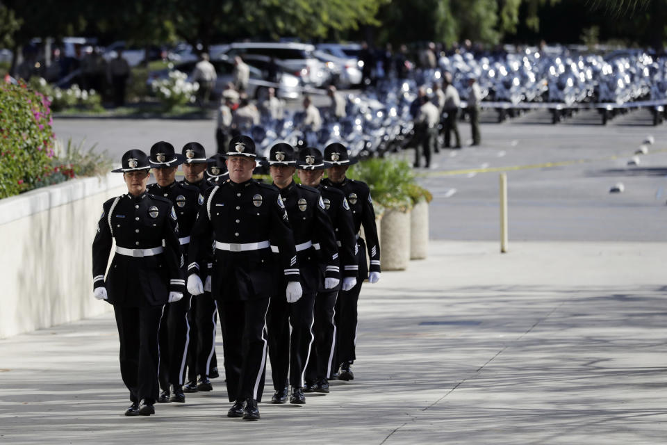 Members of the Santa Ana Police Dept,. march into the Calvary Community Church for a service in memory of Ventura County Sheriff's Sgt. Ron Helus at Thursday, Nov. 15, 2018, in Westlake Village, Calif. Helus was fatally shot while responding to a mass shooting at a country music bar in Southern California. (AP Photo/Marcio Jose Sanchez, Pool)