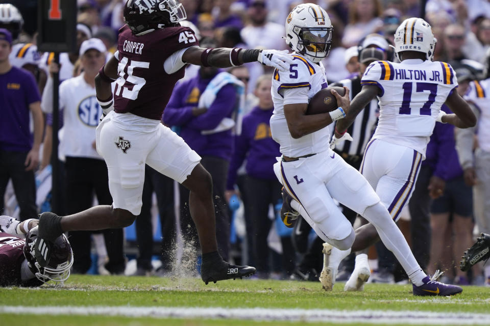 LSU quarterback Jayden Daniels (5) carries past Texas A&M linebacker Edgerrin Cooper (45) in the first half of an NCAA college football game in Baton Rouge, La., Saturday, Nov. 25, 2023. (AP Photo/Gerald Herbert)