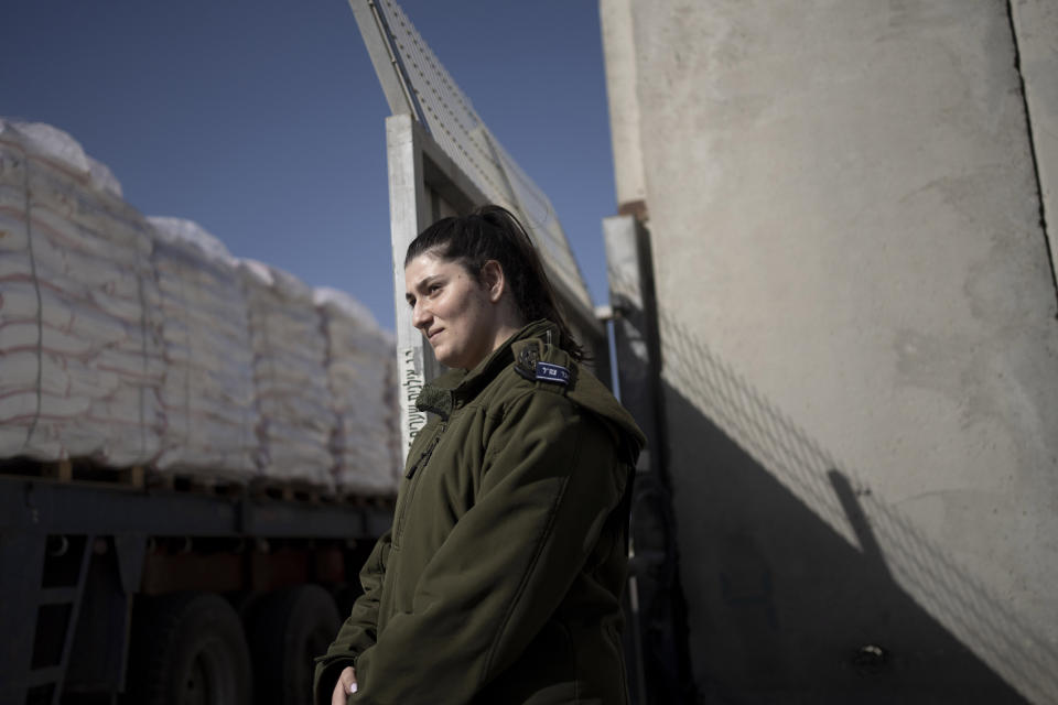 An Israeli soldier stands guard as trucks carrying humanitarian aid bound for the Gaza Strip leave a holding area at Kerem Shalom Crossing on the intersection of two borders between Egypt and southern Israel and the Gaza Strip and southern Israel, Wednesday, Jan. 10, 2024. (AP Photo/Maya Alleruzzo)