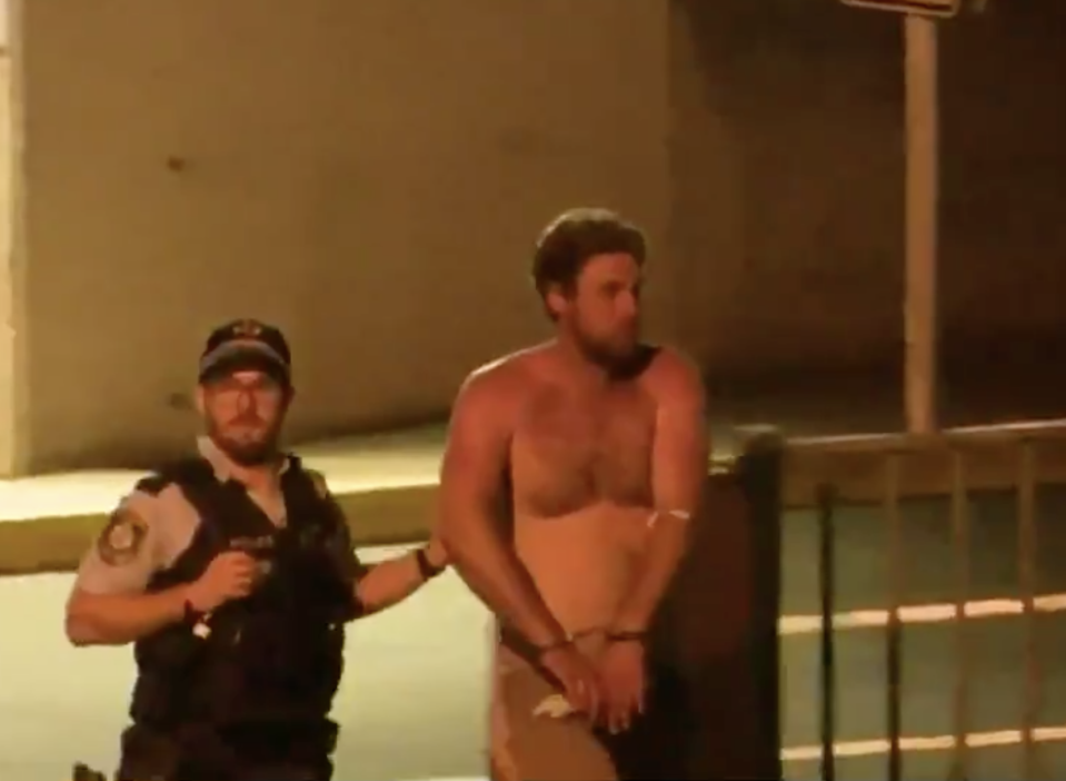 A topless Samuel William Davidson is walked by a police officer on Saturday night. Source: Nine News