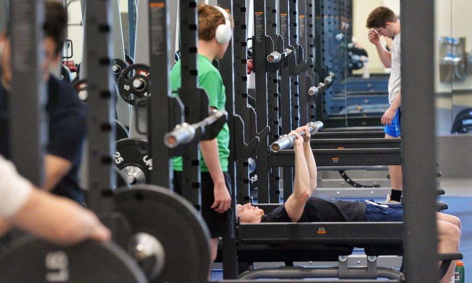 Penn State Behrend freshman Shane Rupert, standing center, and sophomore Tim Compton, on the bench, work out in the new Erie Hall.