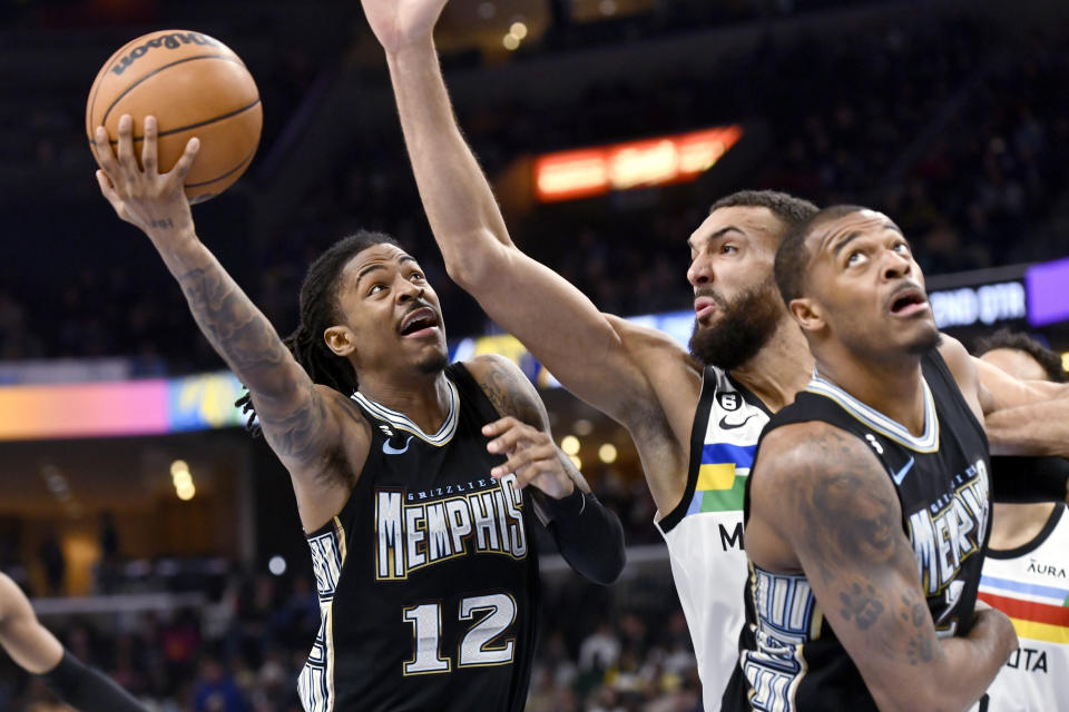 Memphis Grizzlies guard Ja Morant (12) shoots against Minnesota Timberwolves center Rudy Gobert during the first half of an NBA basketball game Friday, Feb. 10, 2023, in Memphis, Tenn. (AP Photo/Brandon Dill)