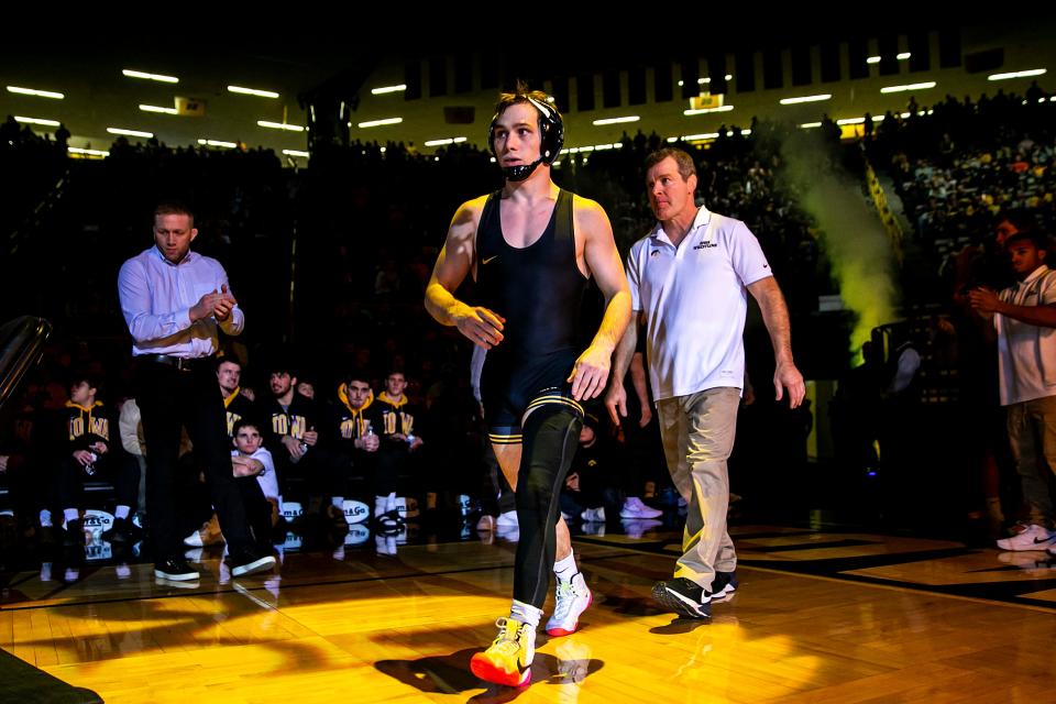Iowa's Spencer Lee, center, is introduced before wrestling at 125 pounds as Iowa head coach Tom Brands, right, looks on during a NCAA Big Ten Conference men's wrestling dual against Illinois, Friday, Jan. 6, 2023, at Carver-Hawkeye Arena in Iowa City, Iowa.