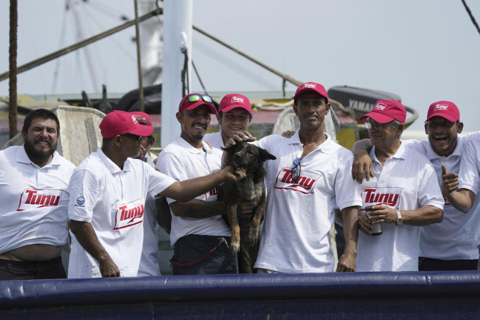 The crew of the Mexican tuna boat "Maria Delia" pose for photos with Bella, the dog of Australian Timothy Lyndsay Shaddock, both of whom they rescued from a incapacitated catamaran in the Pacific Ocean, as they bring the pair to port in Manzanillo, Mexico, Tuesday, July. 18, 2023. After being adrift with his dog for three months, Shaddock and his dog Bella were rescued some 1,200 miles from land. (AP Photo/Fernando Llano)