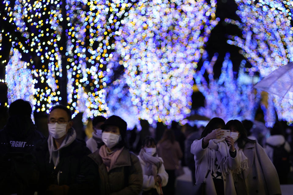 FILE - People wearing a face mask, walk past a Christmas illumination display, at a shopping mall in Yokohama, near Tokyo on Dec. 25, 2021. To contain a deadly delta-driven surge in South Korea, the government this month restored its toughest distancing rules with a four-person limit on private gatherings and a 9 p.m. curfew on restaurants. (AP Photo/Shuji Kajiyama, File)