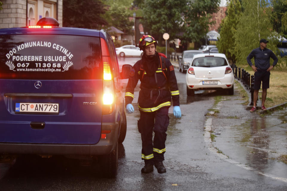 REMOVES SPECIFIC NUMBER OF CASUALTIES AND CLARIFIES SHOOTING DETAILS A firefighter walks by a hearse on the site of the attack in Cetinje, 36 kilometers (22 miles) west of Podgorica, Montenegro, Friday, Aug. 12, 2022. A man went on a shooting rampage in the streets of a western Montenegro city Friday, killing multiple people, before being shot dead by a passerby, officials said. (AP Photo/Risto Bozovic)