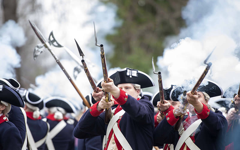People dressed as members of George Washington's Continental Army shoot bayonet rifles
