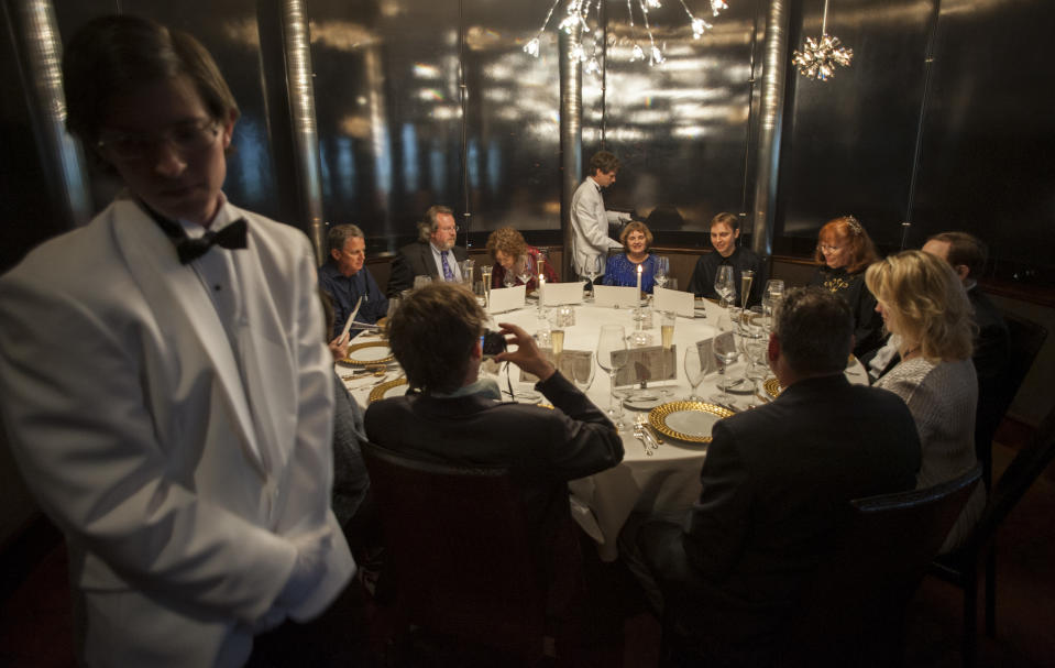 Servers Zack Black, left, and Evan Boyle, center, tend to guests during a re-creation of the final first class dinner served on the RMS Titanic, Saturday, April 14, 2012, in Houston. The Titanic sank in the North Atlantic Ocean April 15, 1912 after colliding with an iceberg during her maiden voyage from Southampton, England to New York. (AP Photo/Dave Einsel)