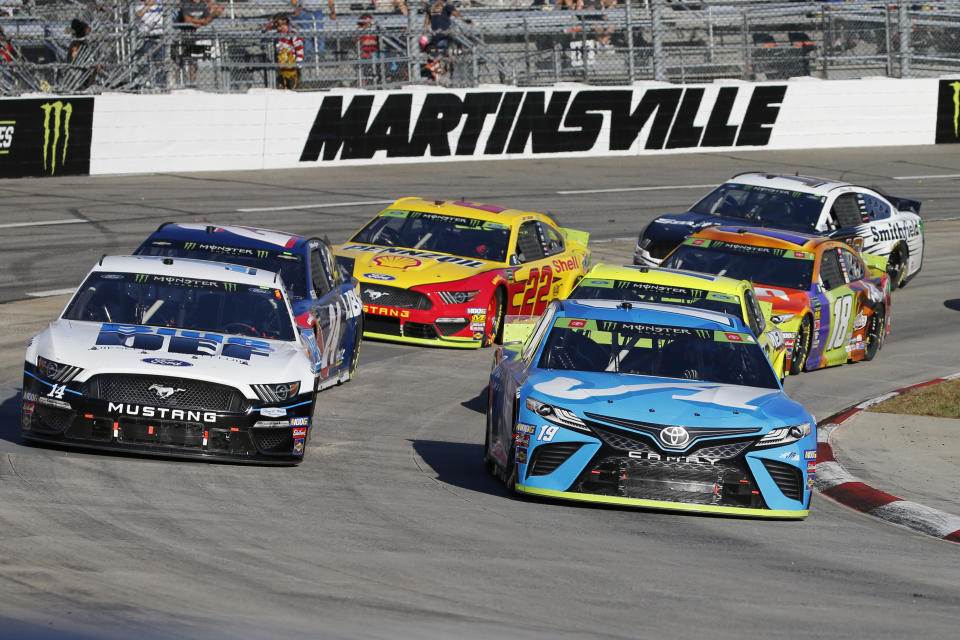 Martin Truex Jr. (19) and Clint Bowyer (14) lead the field in turn four during a restart of the NASCAR Cup Series race at Martinsville Speedway in Martinsville, Va., Sunday, Oct. 27, 2019. (AP Photo/Steve Helber)