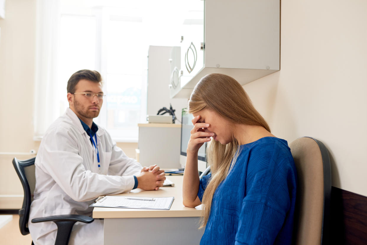 Portrait of sad young woman crying in doctors office consulting about serious illness, copy space