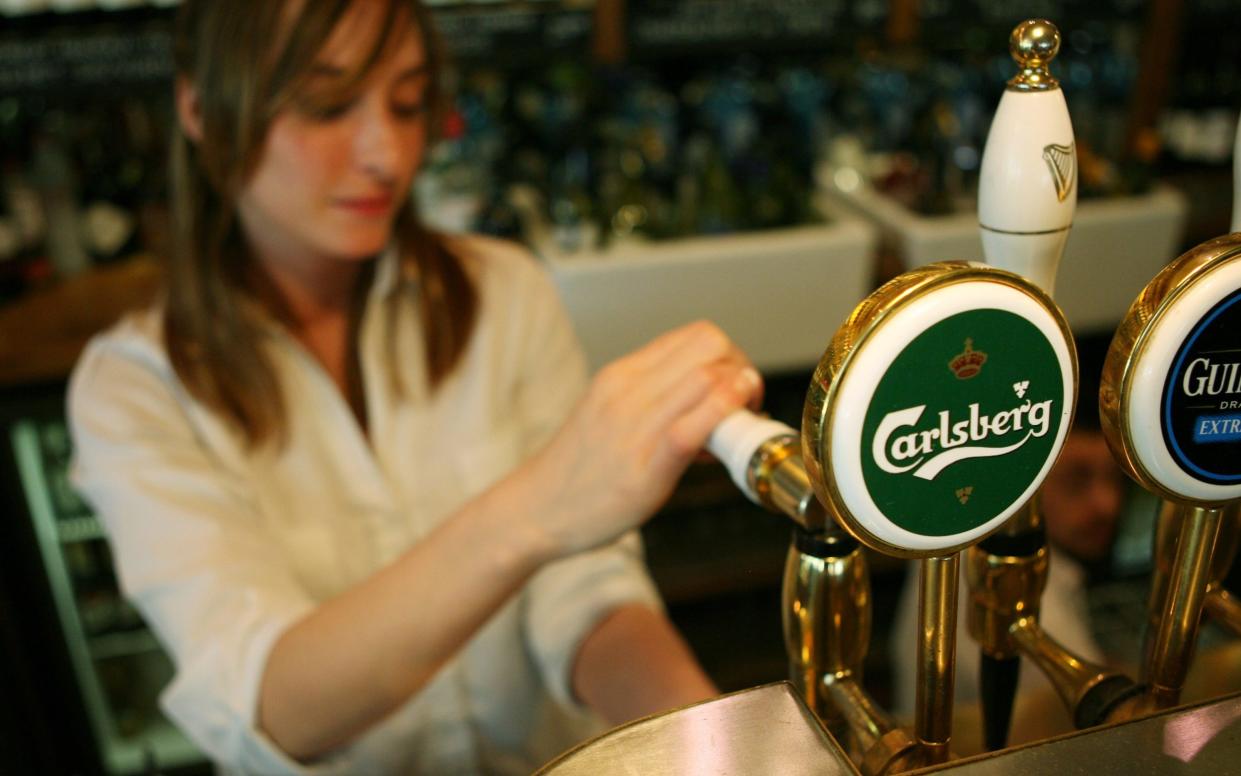 A bartender pulls a pint of Carlsberg lager at a pub in London - Suzanne Plunkett/Bloomberg News