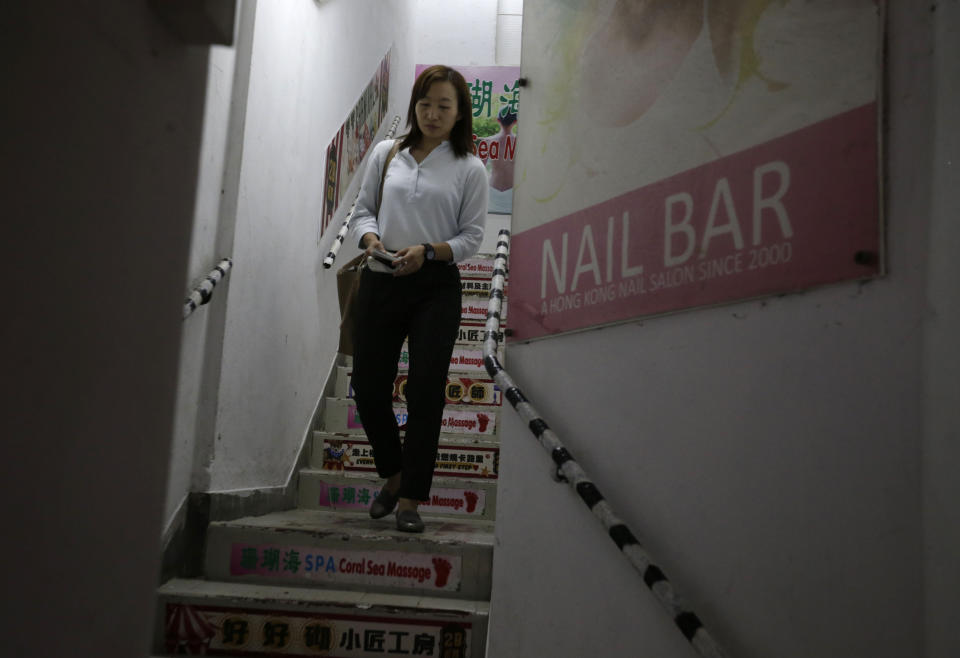 In this photo taken Thursday, Nov. 7, 2019, district council candidate Cathy Yau walks down the stairs of a building during a door-to-door campaign at Causeway Bay in Hong Kong. Yau. a former police officer, grew exasperated as police used more force to quell the unrest. She quit the force in July after 11 years and is running in Sunday's district polls that are widely expected to deliver a decisive victory for the six-month-old movement seeking democratic reforms in the semi-autonomous Chinese territory. (AP Photo/Dita Alangkara)