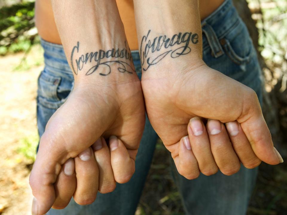 person with compassion and courage tattooed on their wrists