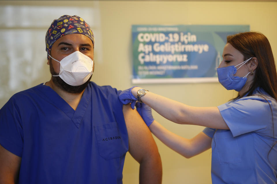 A health worker administers the first dose of a COVID-19 vaccine currently on phase III clinical trials to Cem Gun an Emergency Medicine Physician at the Acibadem Hospital in Istanbul, Friday, Oct. 9, 2020. The vaccine developed in China by Sinovac Biotech, was approved for trials by Health Institutes of Turkey (TUSEB) in 26 private hospitals in the country. (AP Photo/Emrah Gurel)