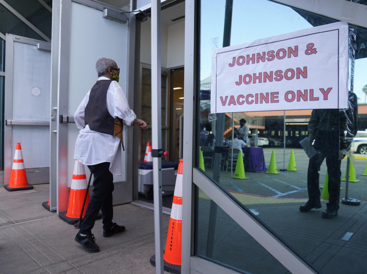  A person wearing a face mask walks into a vaccination site with a sign by the door reading 