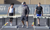 With social distancing in mind, a coach stands by as student athletes run a drill during a strength and conditioning camp at Arlington Martin High School Thursday, June 18, 2020, in Arlington, Texas. While states have been easing the economic and social lockdowns prompted by the coronavirus pandemic, some are now letting high school athletes return for summer workouts before teachers have even figured out how they are going to hold classroom instruction. (AP Photo/LM Otero)