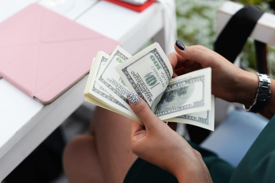 business beautiful girl holding in hands with clock currency dollars to settle for expense in restaurant, woman sitting at table with tablet and counting money cash