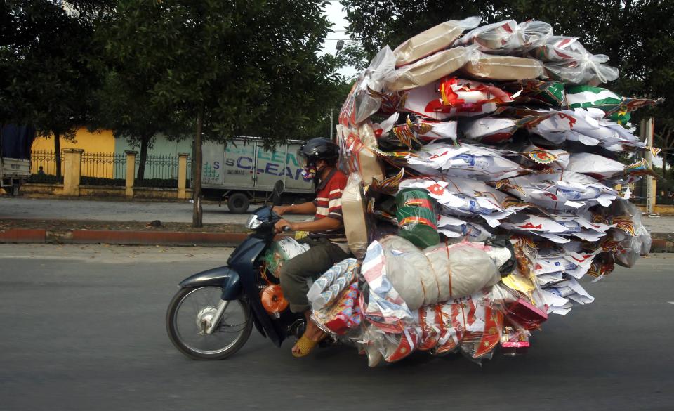 A man transports paper replicas of various items to be sold for the Vu Lan Festival out of Dong Ho village, outside Hanoi August 7, 2014. Vietnam is celebrating the month-long festival of the hungry ghosts, also known as Vu Lan festival, where many Taoists and Buddhists believe that the living are supposed to please the ghosts by offering them food and burning paper effigies of homes, maids, and other daily items for spirits to use in the afterlife. REUTERS/Kham (VIETNAM - Tags: RELIGION SOCIETY TRANSPORT)