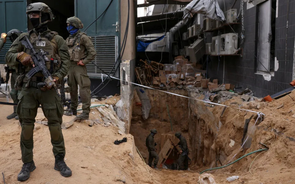 Israeli soldiers stand near the opening to a tunnel at Al-Shifa hospital