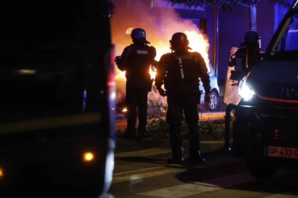 Riot police stand near a burning car in the La Meinau neighborhood of Strasbourg, eastern France, on Friday, June 30, 2023. Young rioters clashed with police and looted stores Friday in a fourth day of violence triggered by the deadly police shooting of a teen, piling more pressure on President Emmanuel Macron after he appealed to parents to keep children off the streets and blamed social media for fueling unrest. (AP Photo/Jean-Francois Badias)