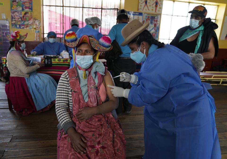 A health worker gives a shot of the Sinopharm vaccine for COVID-19 to Yolanda Coila, during a vaccine campaign in Jochi San Francisco, Peru, Friday, Oct. 29, 2021. While more than 55% of Peruvians have gotten at least one shot of COVID-19 vaccines, only about 25% of people in Indigenous areas have been vaccinated. (AP Photo/Martin Mejia)