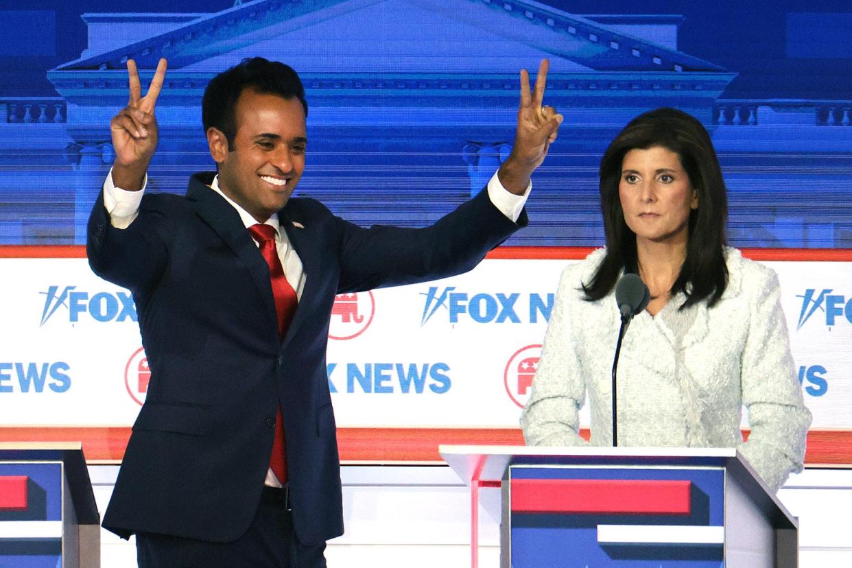 A grinning Ramaswamy holds both hands aloft making "victory" signs towards the audience while Haley stares wistfully into the middle distance.