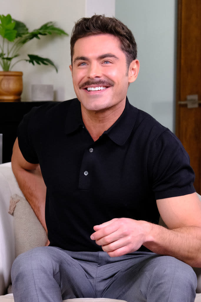 Zac Efron sitting on a chair and smiling