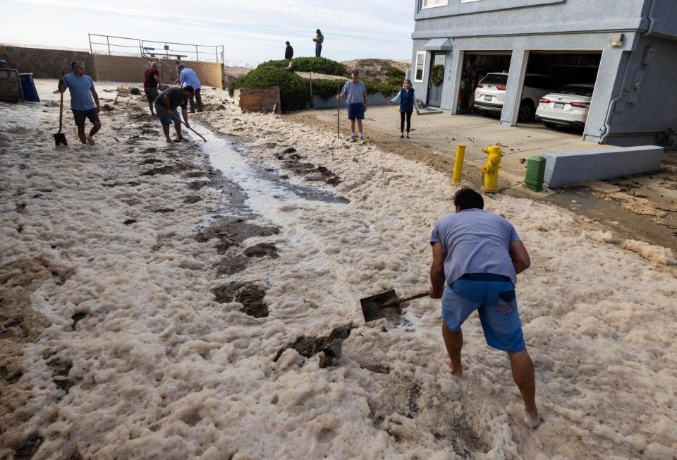 Pierpont neighbors help shovel sand on Bath Lane to help water drain in Ventura.