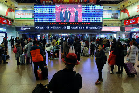 People watch the CCTV Spring Festival Gala TV show on a screen at the Beijing West train station in Beijing, China, January 15, 2018. REUTERS/Thomas Peter