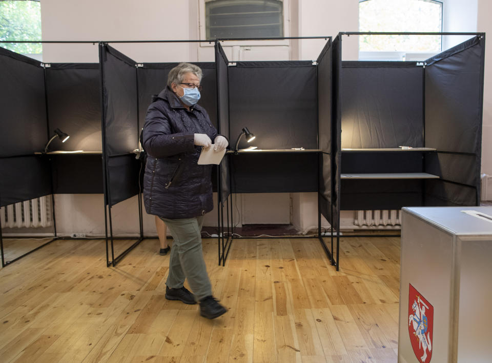 A woman, wearing a face mask to protect against coronavirus walks to cast her ballot at a polling station during parliamentary elections in Vilnius, Lithuania, Sunday, Oct.11, 2020. Polls opened Sunday for the first round of national election in Lithuania, where voters will renew the 141-seat parliament and the ruling four-party coalition is widely expected to face a stiff challenge from the opposition to remain in office. (AP Photo/Mindaugas Kulbis)