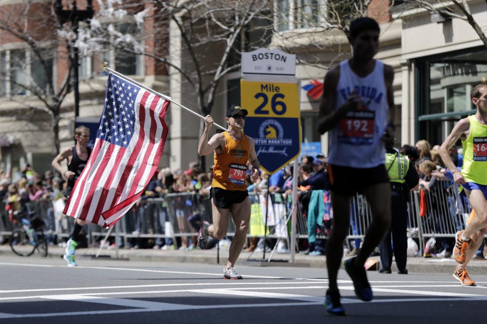 Donny Sazama, of Hermantown, Minn., carries an American flag as he runs past the 26 mile mark of the 118th Boston Marathon Monday, April 21, 2014 in Boston. (AP Photo/Robert F. Bukaty)