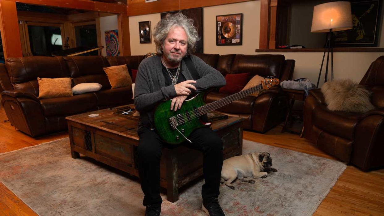  Steve Lukather at home cradling a guitar with a pug at his feet  
