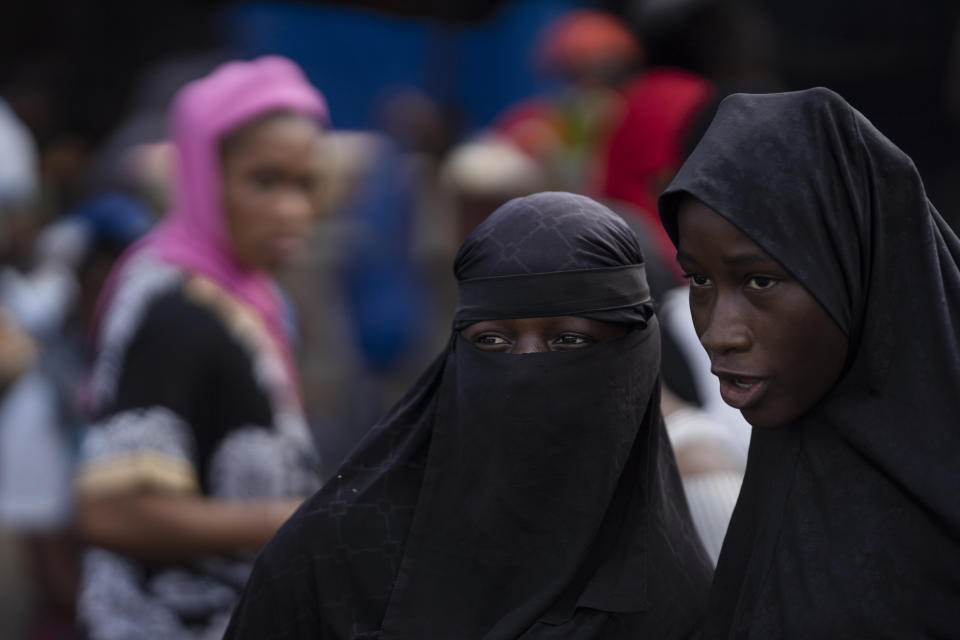 Two women look on as they stand at a market in Abobo neighborhood, in the suburbs of Abidjan, Ivory Coast, Sunday, Nov. 1, 2020. Ivory Coast's main opposition parties boycotted the presidential vote on Saturday, and asserted that at least a dozen people had died in election day clashes as incumbent leader Alassane Ouattara sought to be elected for a controversial third term in office. (AP Photo/Leo Correa)