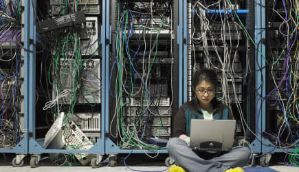 Young woman using laptop in server room