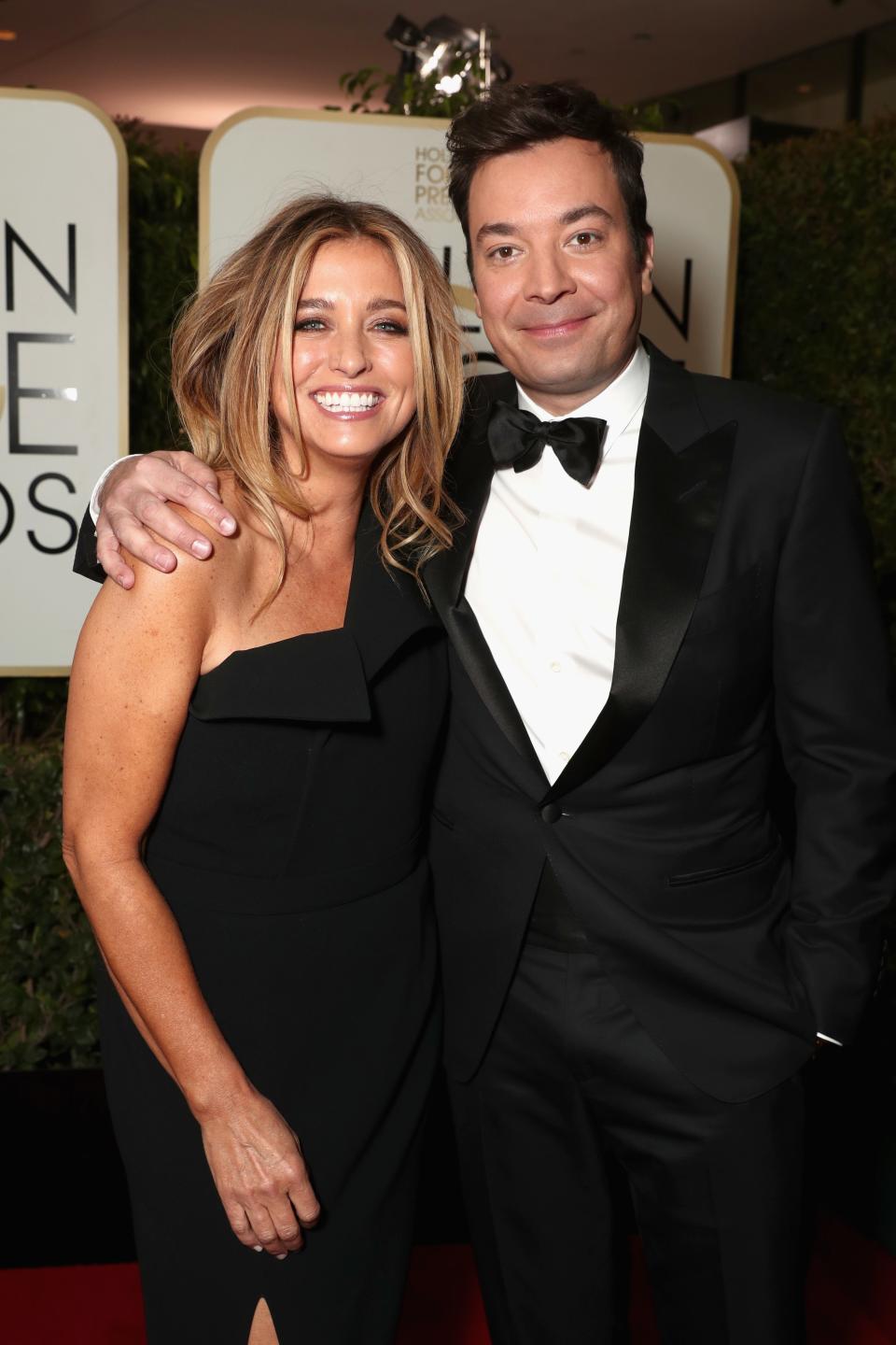 Jimmy Fallon and Nancy Juvonen pose together on the red carpet, with Jimmy wearing a tuxedo and Nancy in an elegant one-shoulder dress