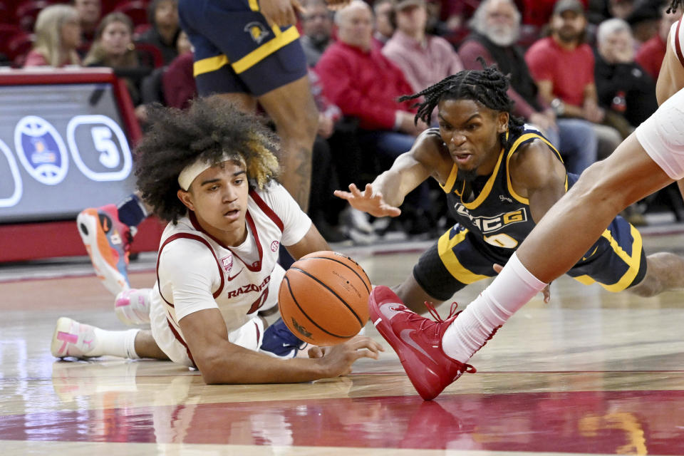 Arkansas guard Anthony Black, left, and UNC Greensboro guard Keyshaun Langley dive for the ball during the first half of an NCAA college basketball game Tuesday, Dec. 6, 2022, in Fayetteville, Ark. (AP Photo/Michael Woods)