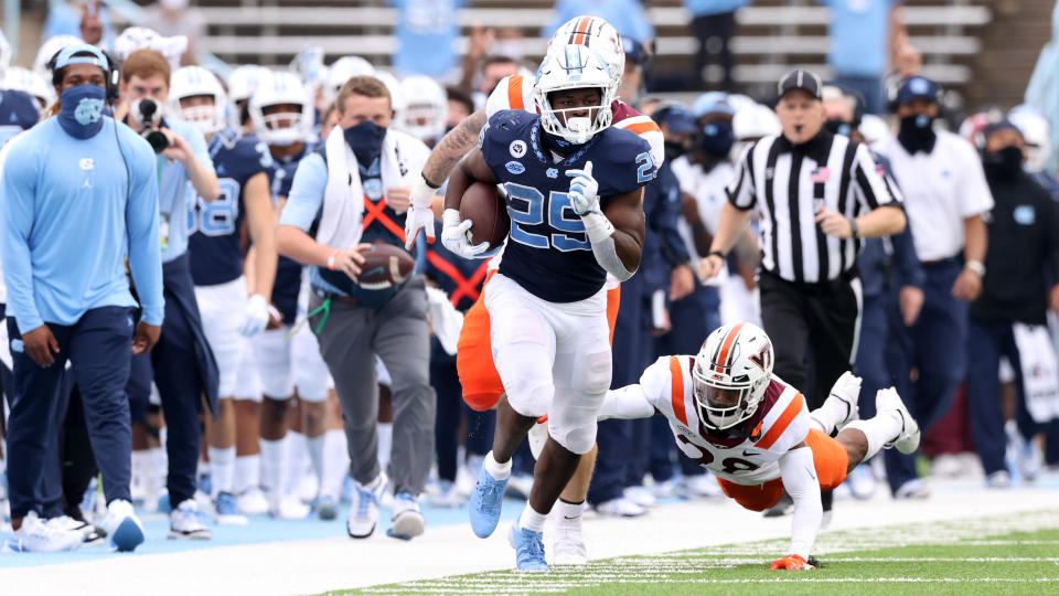 CHAPEL HILL, NC - OCTOBER 10: Javonte Williams #25 of North Carolina is chased by a diving Jermaine Waller #28 of Virginia Tech on a 29-yard run during a game between Virginia Tech and North Carolina at Kenan Memorial Stadium on October 10, 2020 in Chapel Hill, North Carolina. (Photo by Andy Mead/ISI Photos/Getty Images)